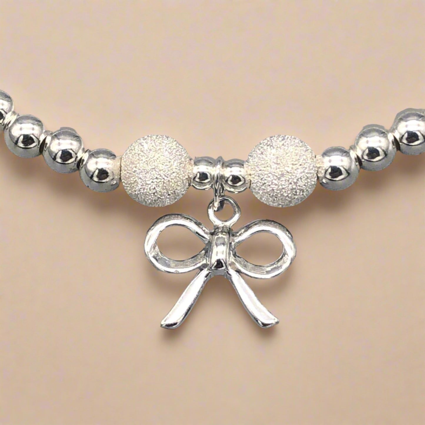 Closeup of Ribbon bow charm sterling silver stacking bracelet for her by My Silver Wish