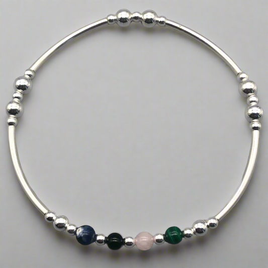 Silver bracelet with colorful beads on a gray background
