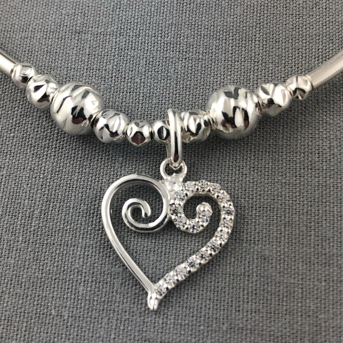 Closeup of Swirl heart charm sterling silver stacking charm bracelet by My Silver Wish