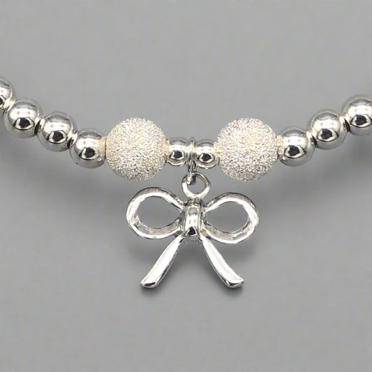 Closeup of Ribbon bow charm sterling silver stacking bracelet for her by My Silver Wish by My Silver Wish