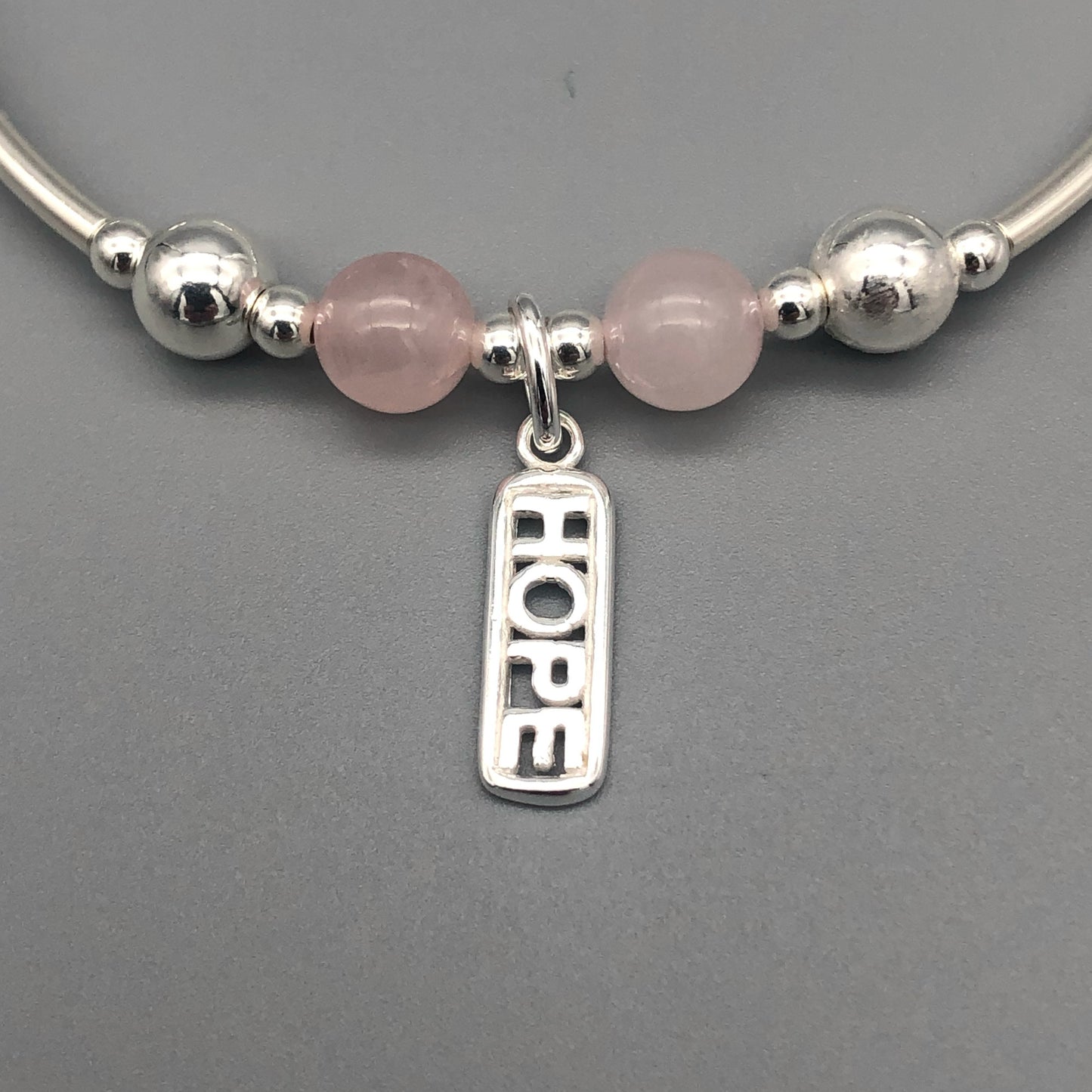 Closeup of "Hope" rose quartz healing crystal women's silver stacking charm bracelet by My Silver Wish