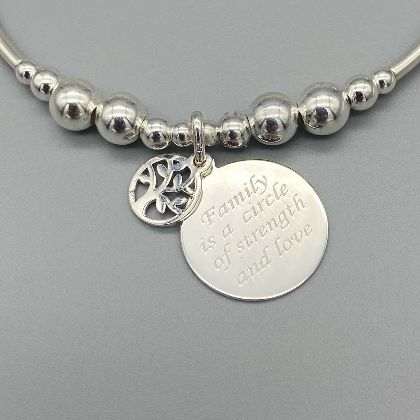 Closeup of "Family is a Circle of Strength & Love" charm sterling silver stacking bracelet for her by My Silver Wish