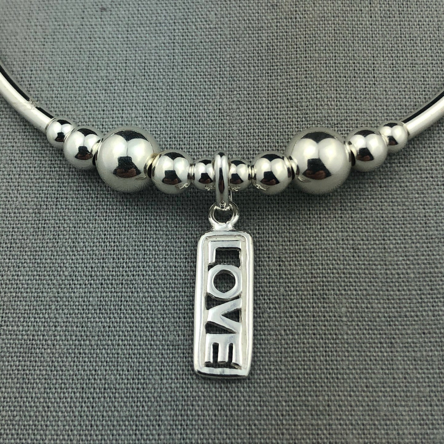 Closeup of "Love" tag charm sterling silver stacking charm bracelet by My Silver Wish