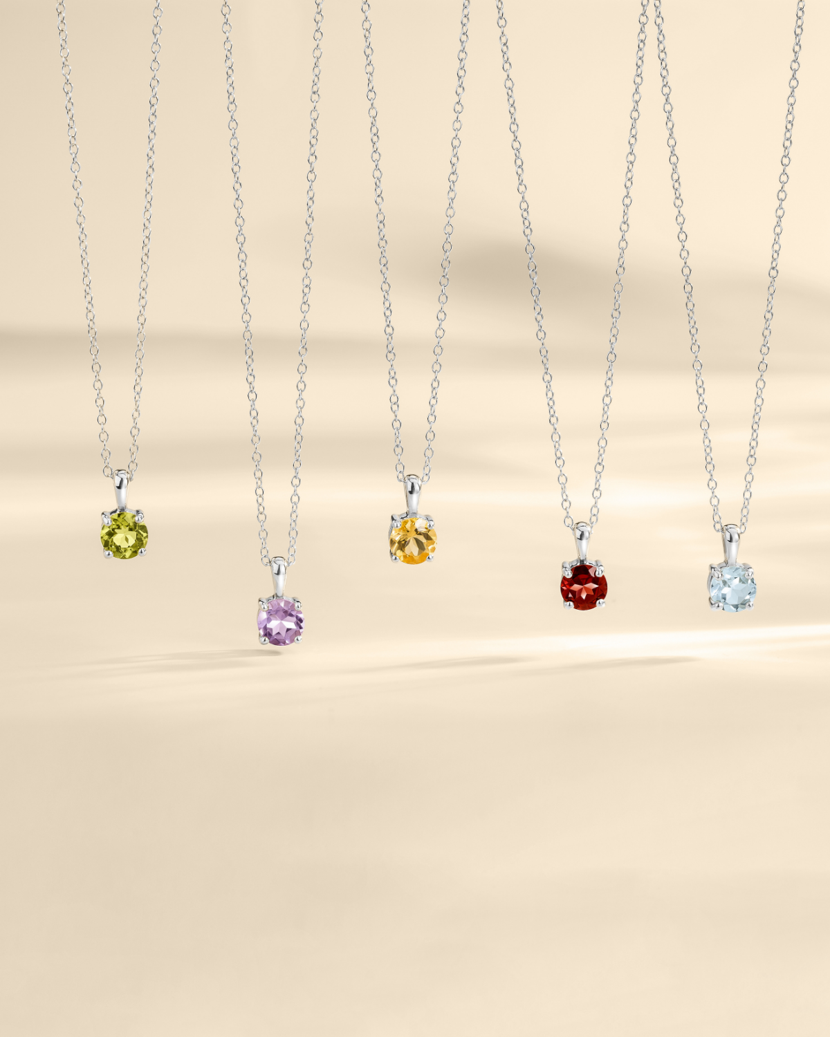 Five necklaces with colored gemstones on a beige background