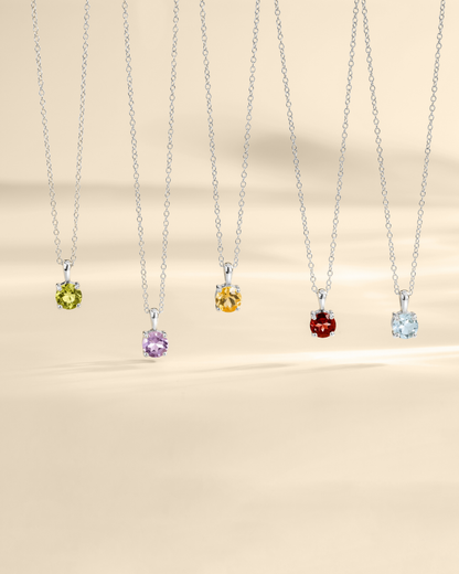 Five necklaces with colored gemstones on a beige background