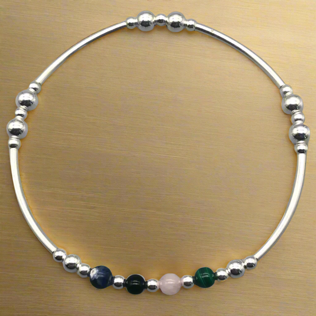 Silver beaded bracelet with colored beads on a gold background
