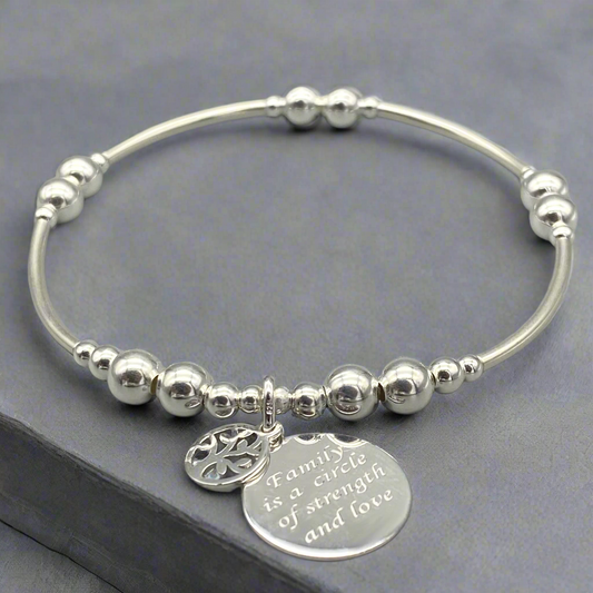 Silver bracelet with beads and engraved charm on a gray background