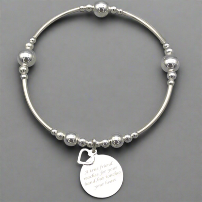 Silver bracelet with a heart-shaped tag on a gray background