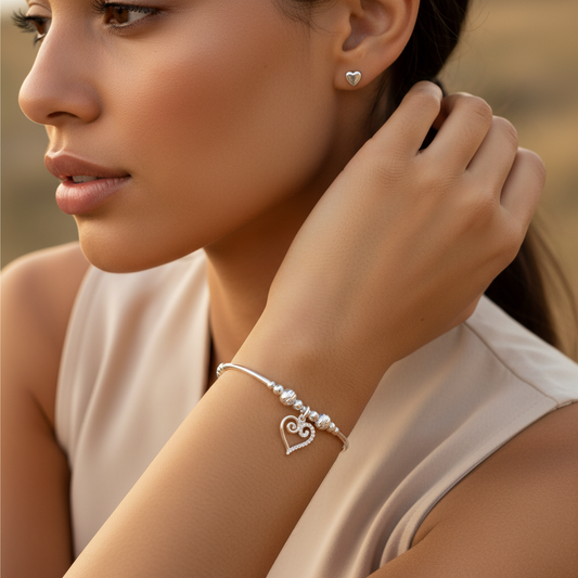 Model wearing a Scroll heart charm sterling silver hand-made women's stacking bracelet and earring gift set by My Silver Wish